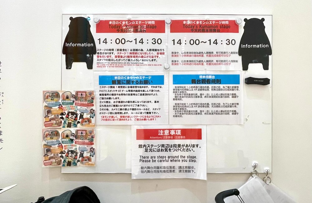 くまモンスクエアのステージ案内掲示板。ステージ時間や注意事項が日本語と英語で書かれている。