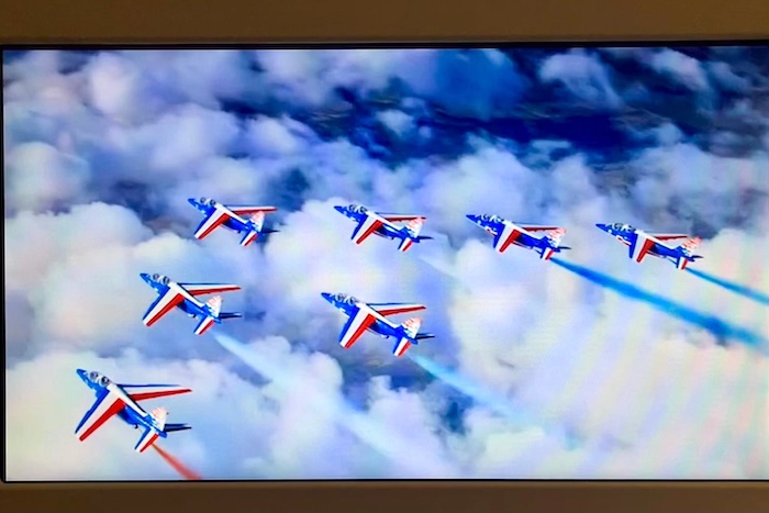 雲海の上を、フランス国旗のカラーを纏った8機のジェット機がダイナミックに旋回する様子。