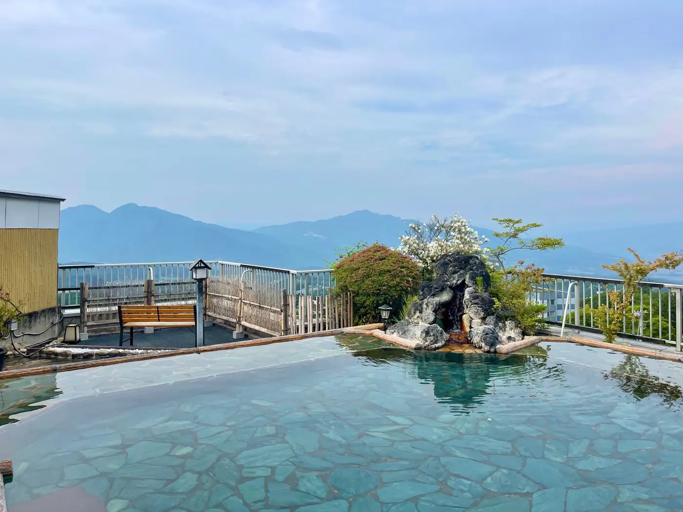 岩を組んだ湯だまりと庭園に置かれたベンチ