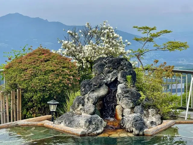花々に包まれる岩組みの湯の湧き出し口